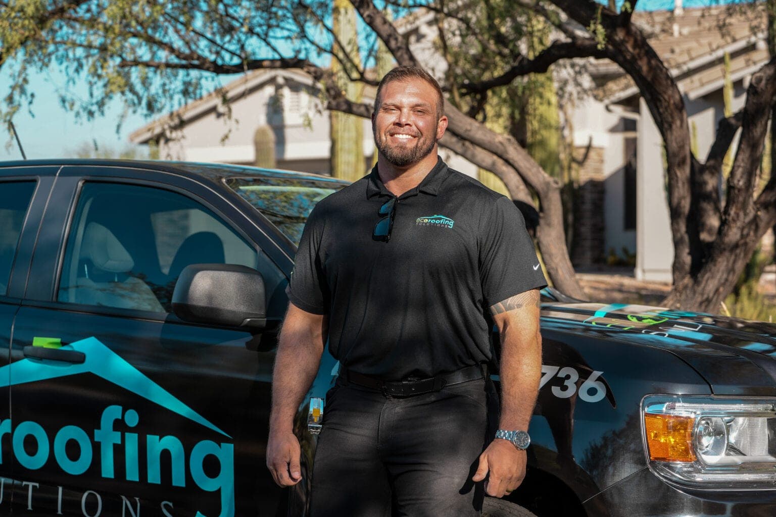Eco Roofing Solutions team member standing beside a branded company truck outside an Arizona home