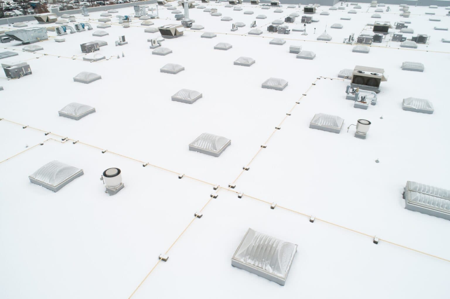 Aerial view of a large white commercial flat roof dotted with skylights and rooftop HVAC units