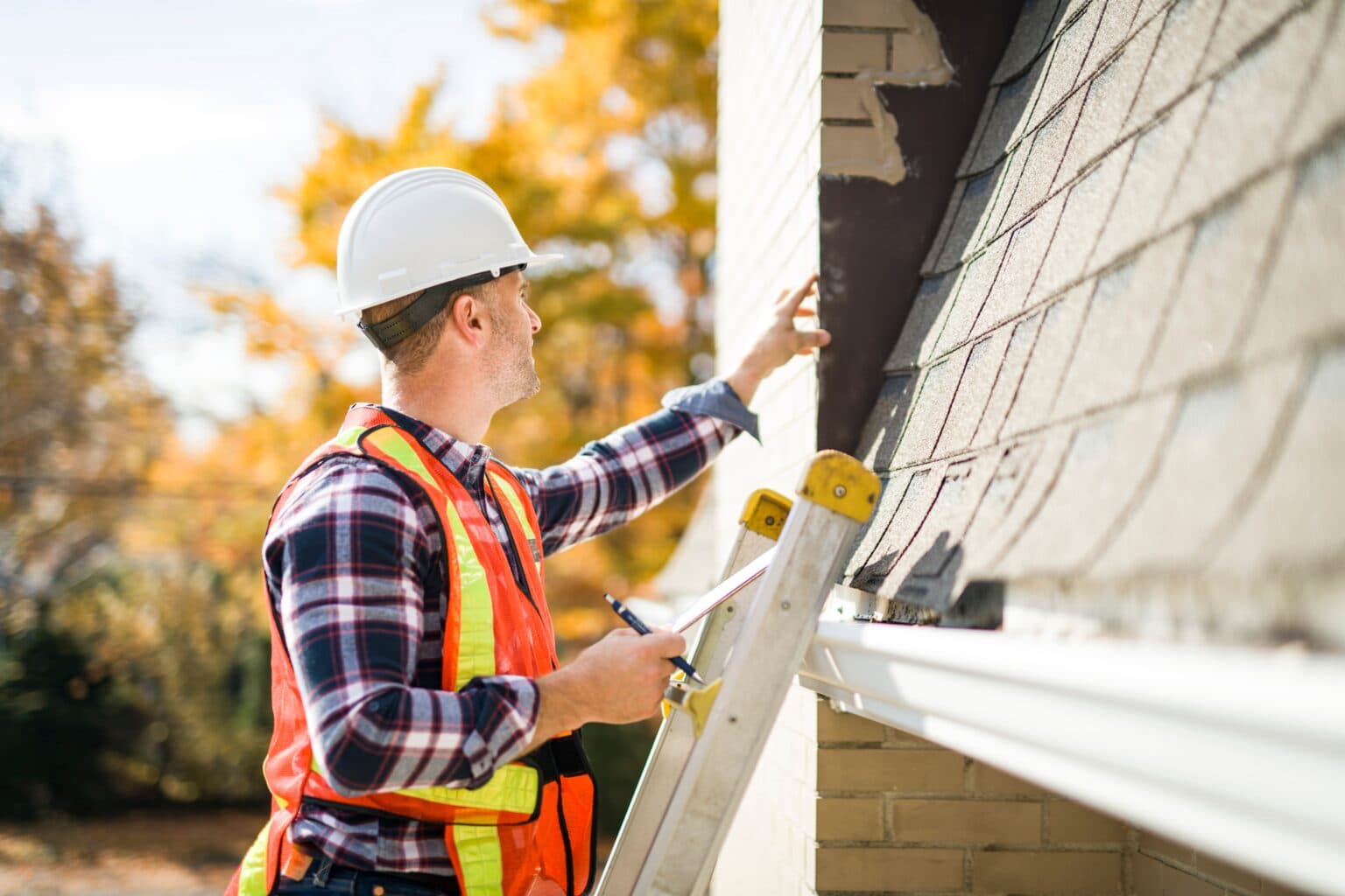 Roof inspector on a ladder checking the shingle edge and gutter line of a house