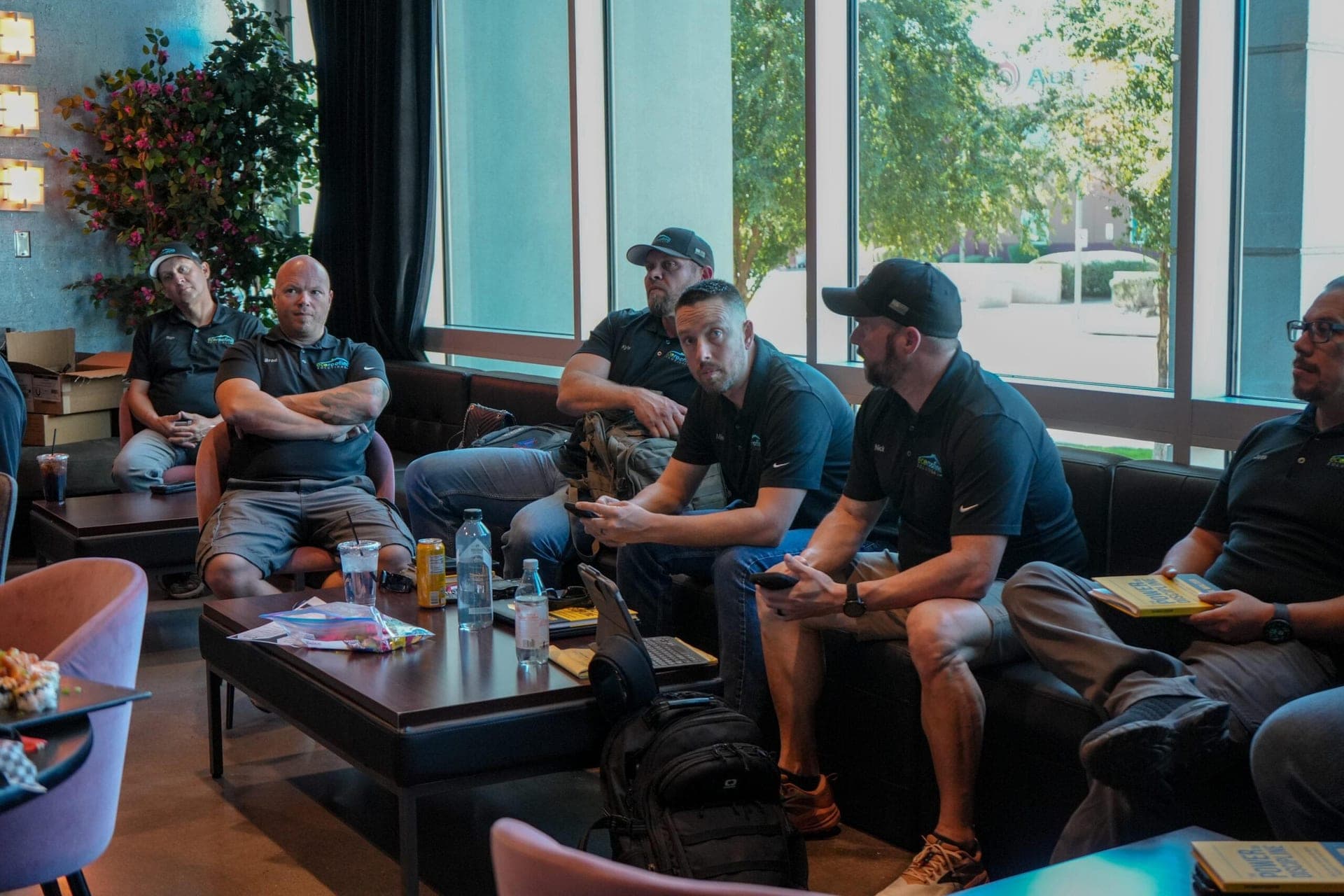 Eco Roofing Solutions crew members in branded polo shirts sitting together during a team meeting