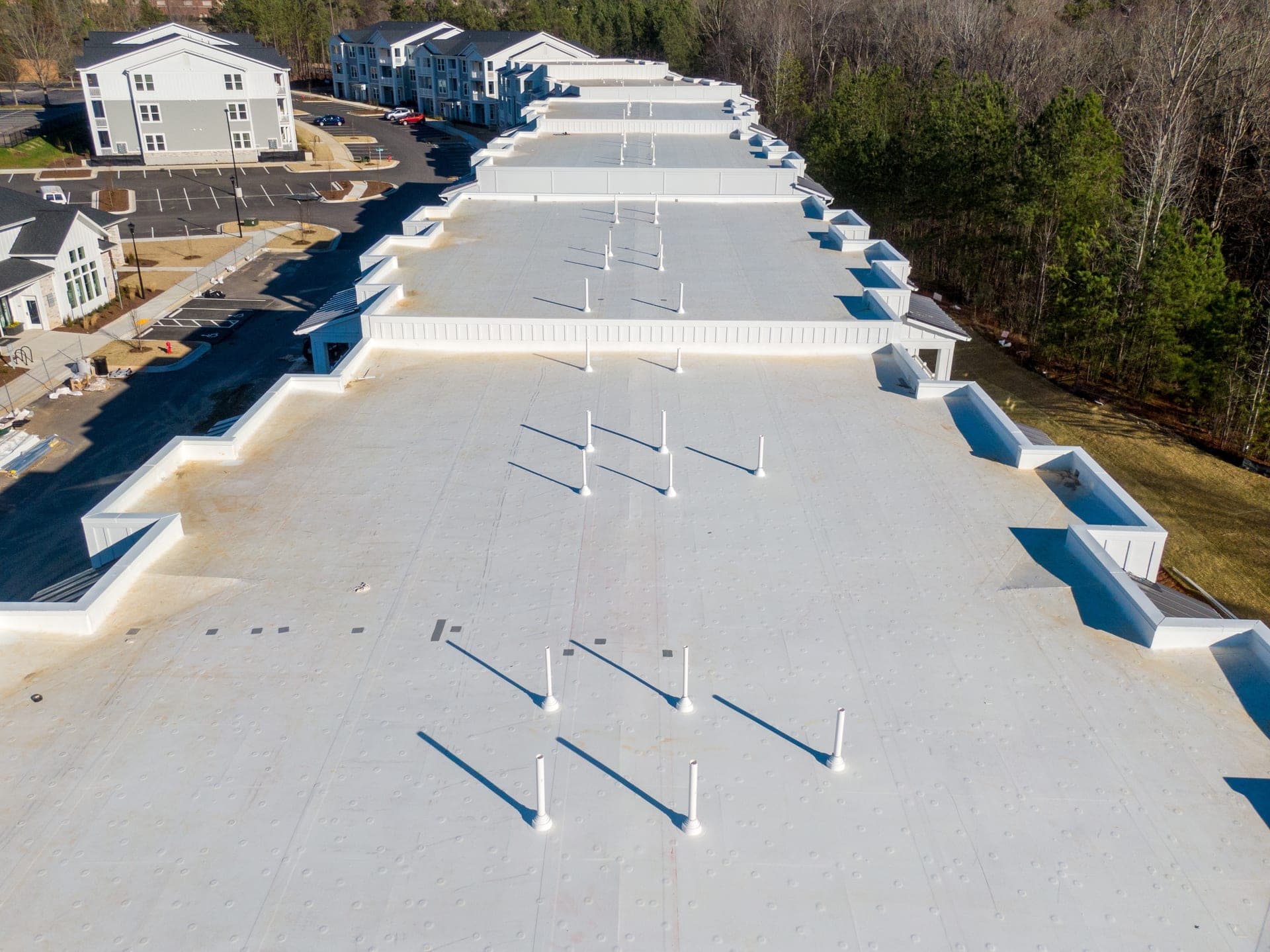 Aerial view of a newly installed white TPO flat roof system on a large multi-building commercial property